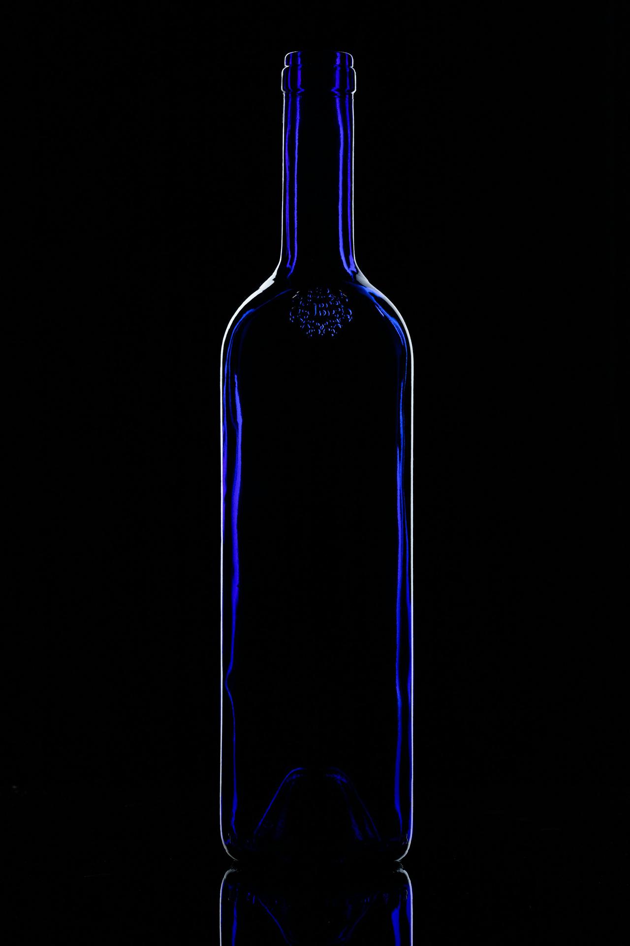 Blue wine bottle. Dark field.